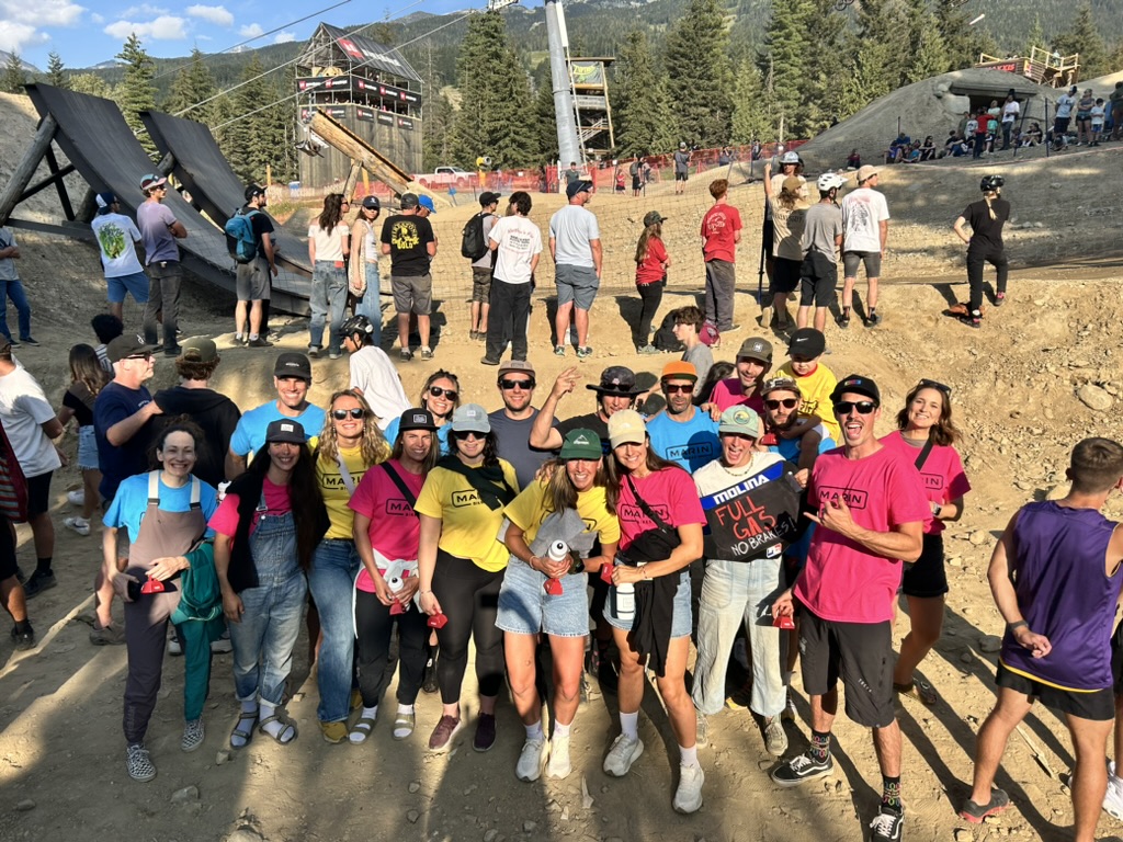 A group of Marin mountain bikers posing for a picture beside the slopestyle jumps of whistler bike park